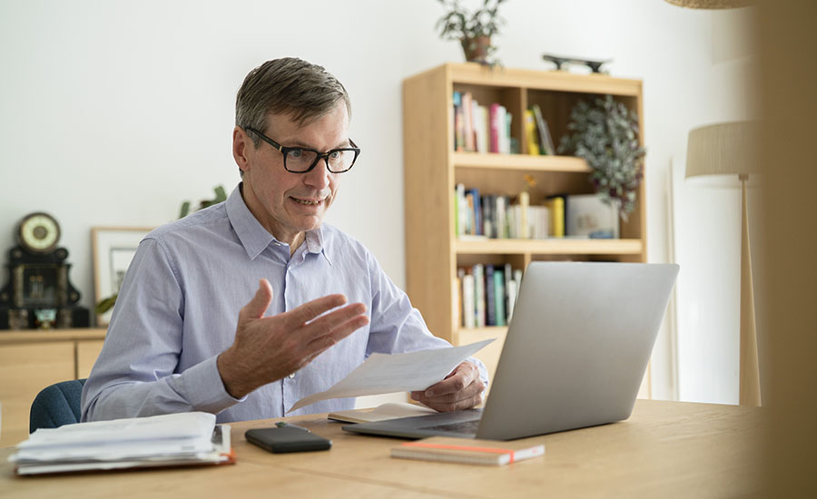 Online Experience. Senior businessman having an online meeting while doing home office.