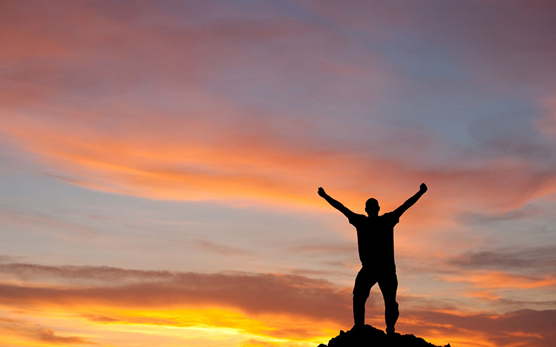 USC Distinguished Leaders Program unique approach - Personal and Professional Longevity. Silhouette of Man Lifting Arms in Joy.